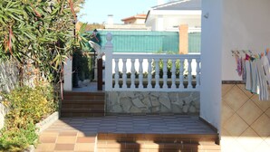 A paved entrance with steps leading to a white gate, a stone wall, and a tiled wall with hanging laundry. - Casa flamenca en El Ventorrillo (Cullar Vega)