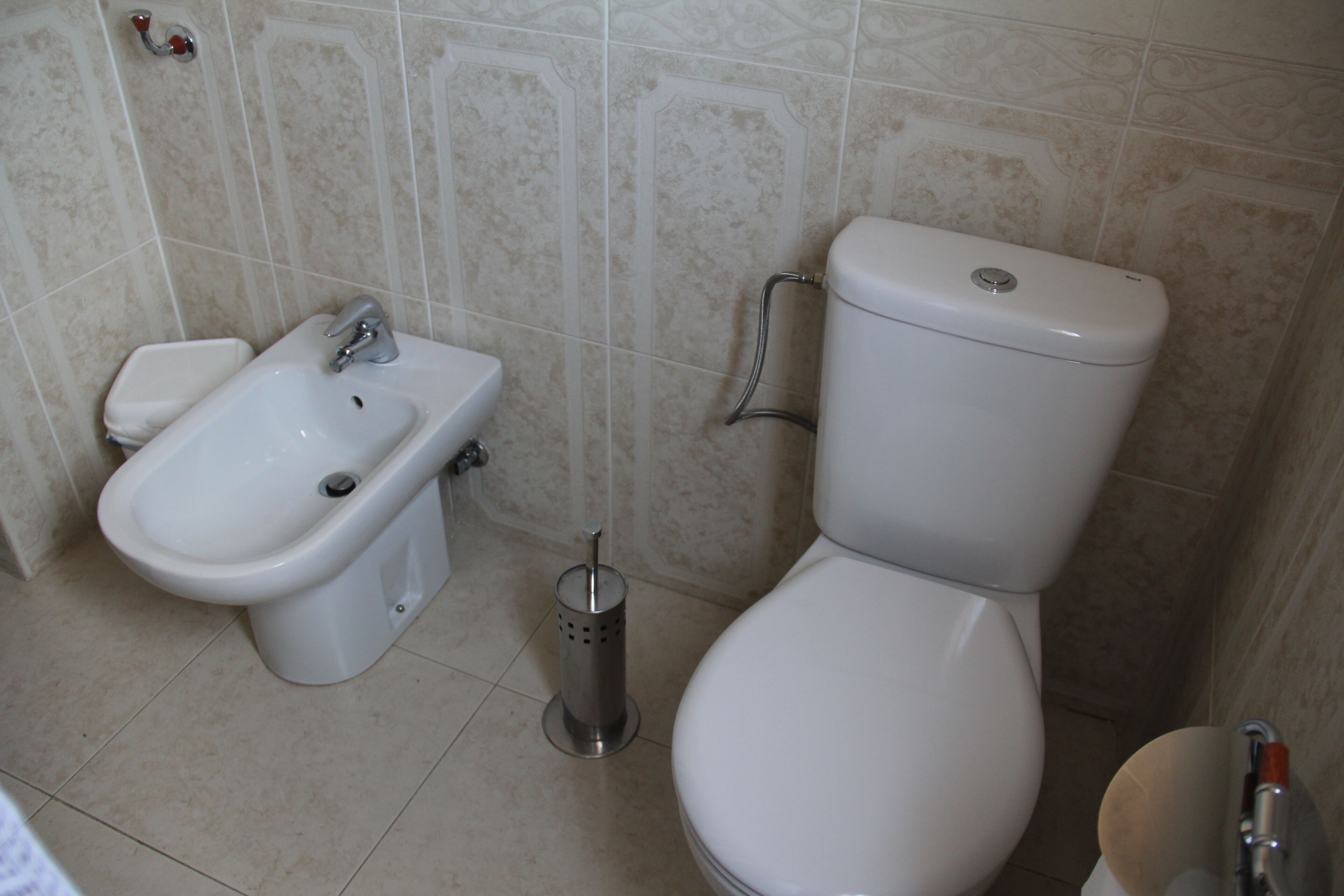 A bathroom with a bidet, toilet, and sink.