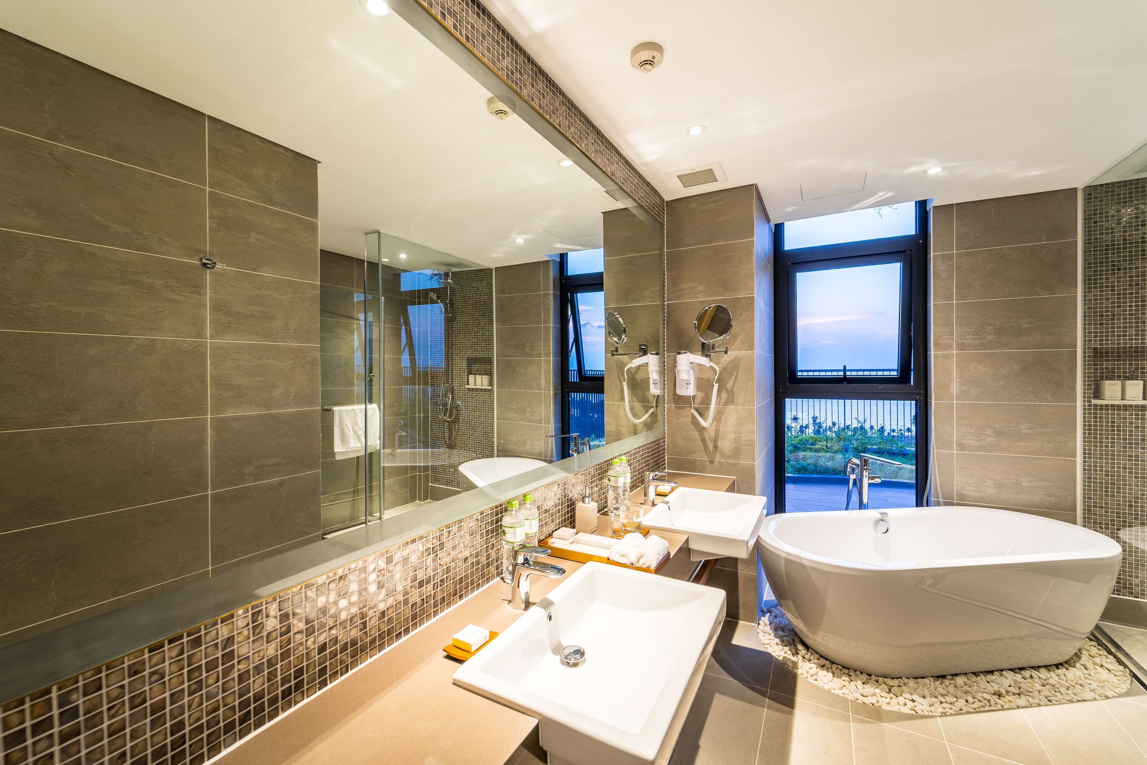 A modern bathroom with a large bathtub, two sinks, and a large mirror.