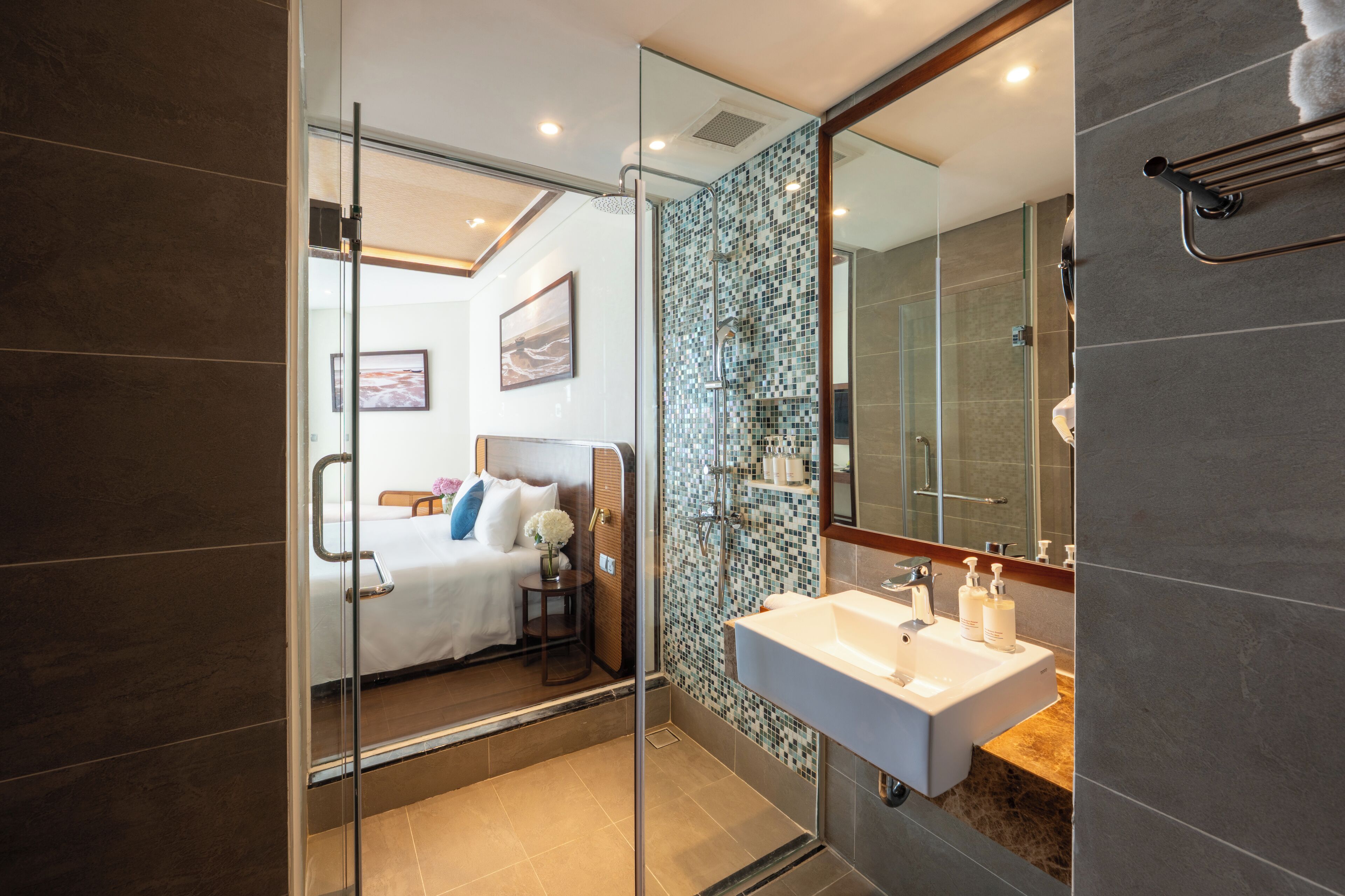 A modern bathroom with a glass shower enclosure, a large mirror, and a white sink with toiletries.