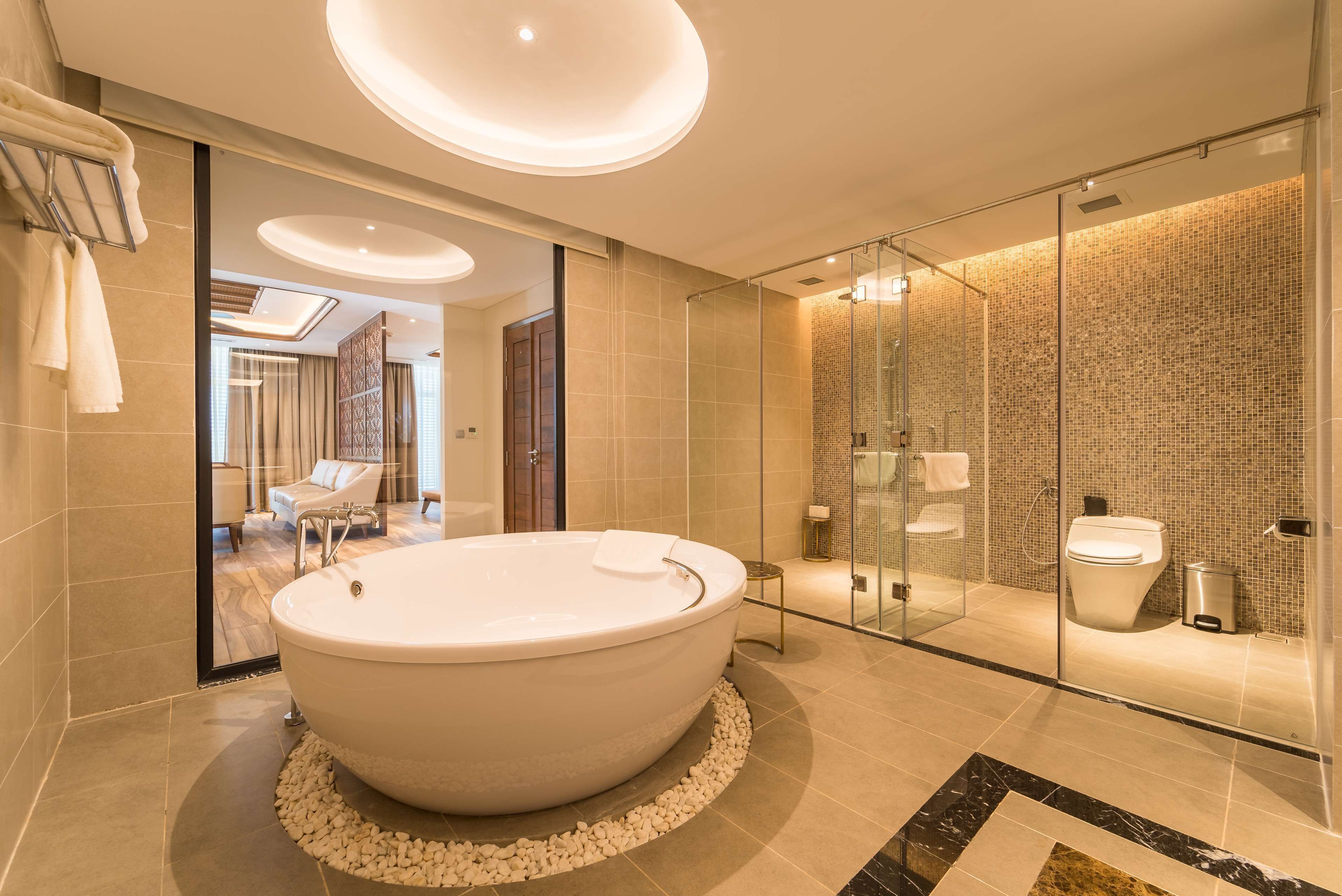 A modern bathroom with a large freestanding bathtub, a glass-enclosed shower, and a visible toilet.