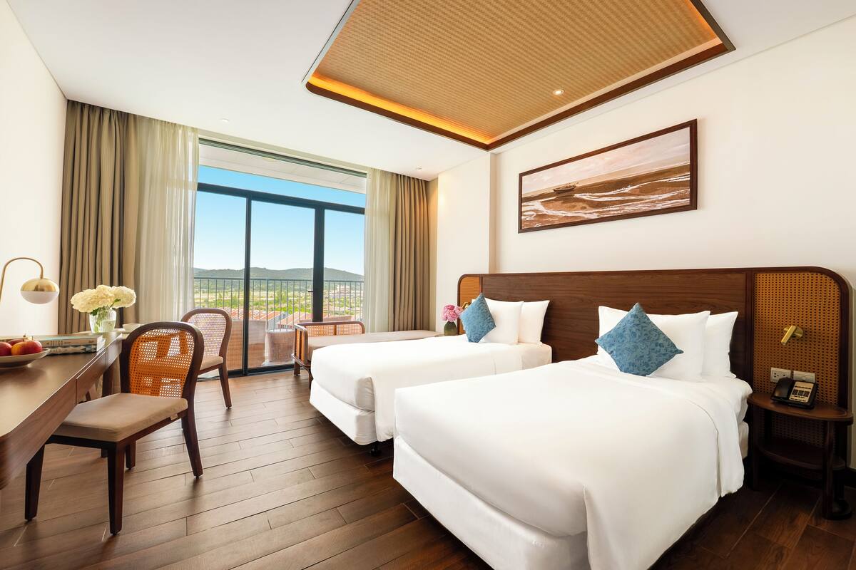 Ein Hotelzimmer mit zwei Betten, einem Schreibtisch und einem Stuhl.