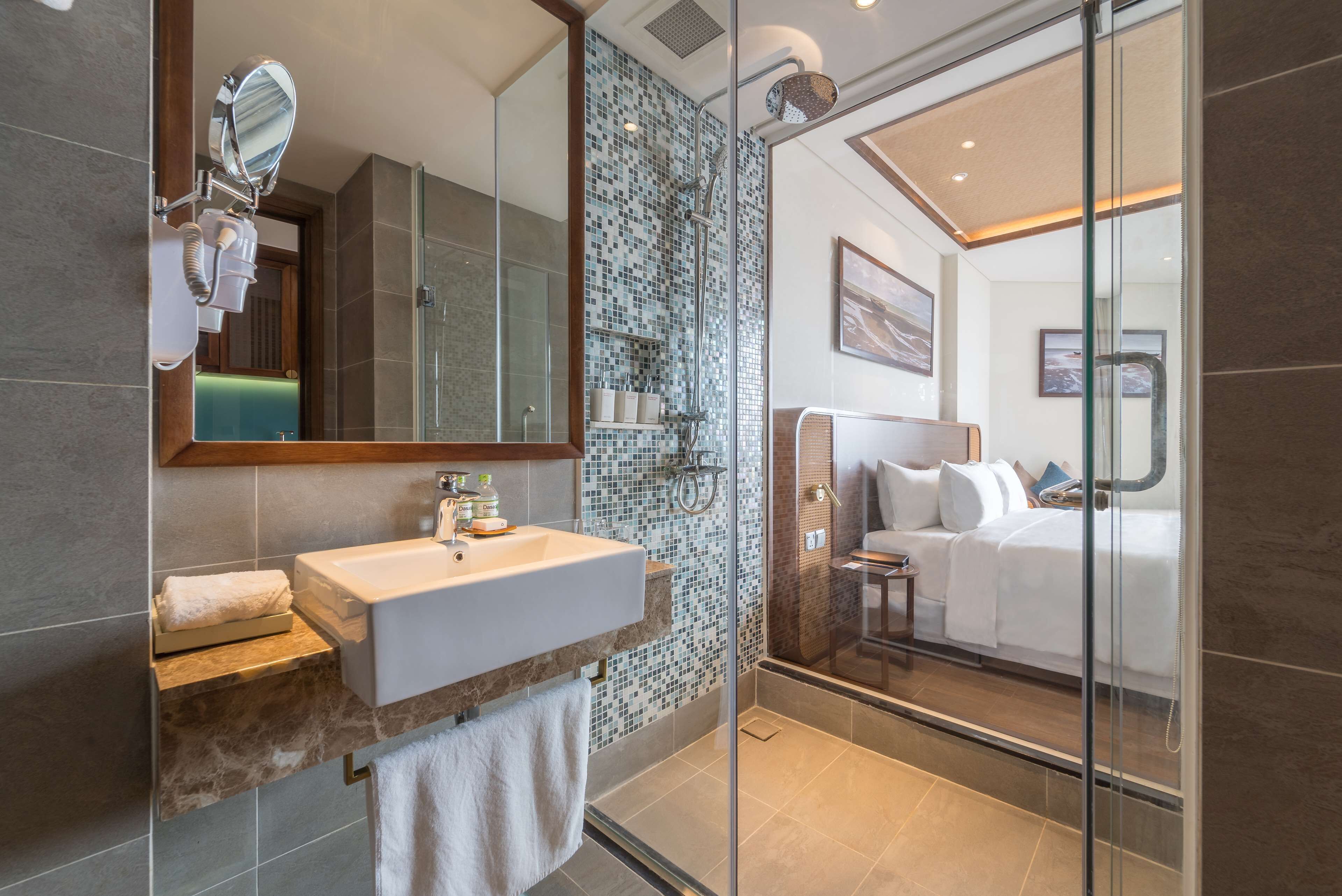 Une salle de bain moderne avec une douche à l’italienne en verre, un grand miroir et un lavabo blanc.