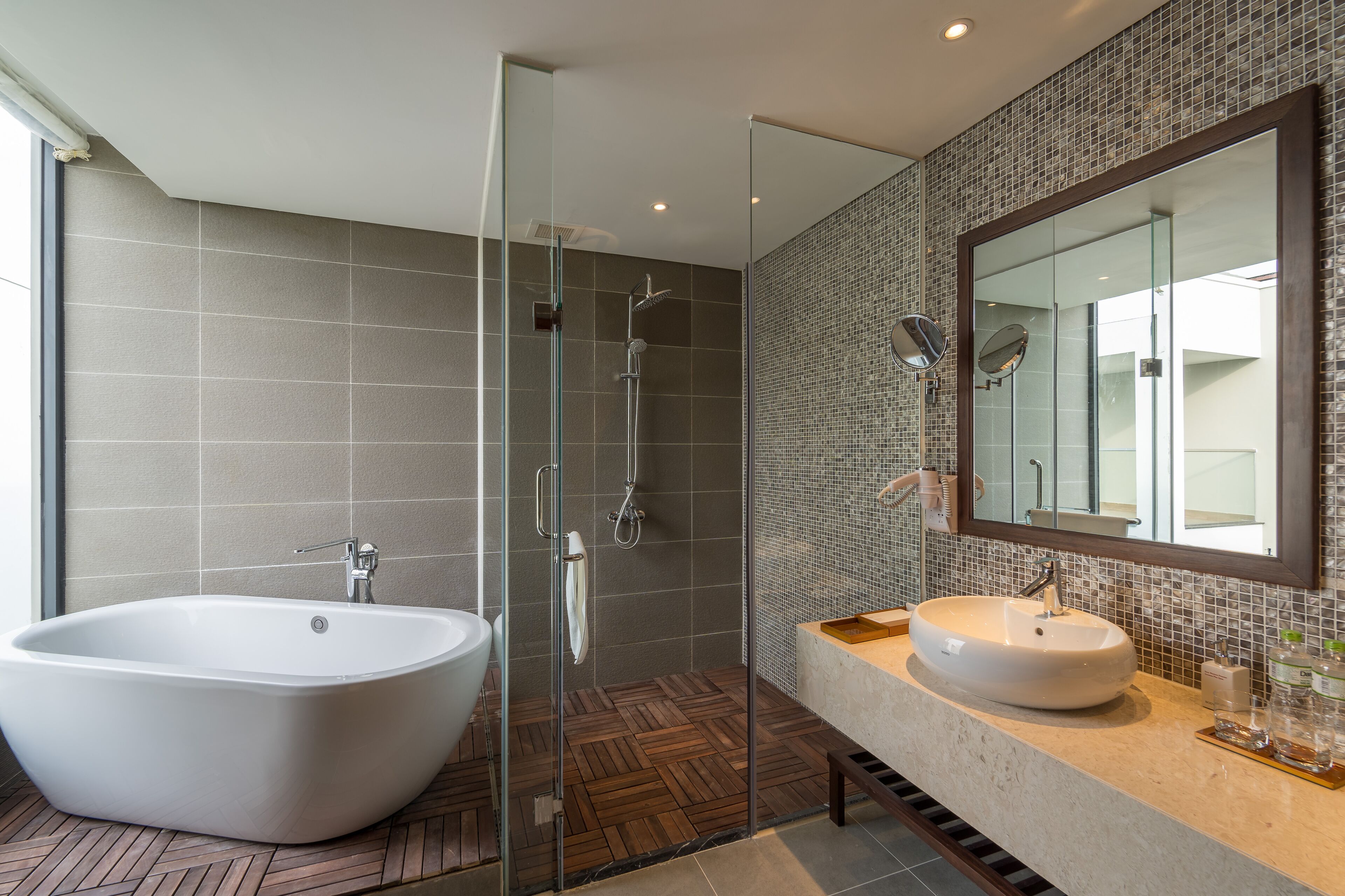A modern bathroom with a freestanding bathtub, a glass-enclosed shower, and a large mirror above the sink.