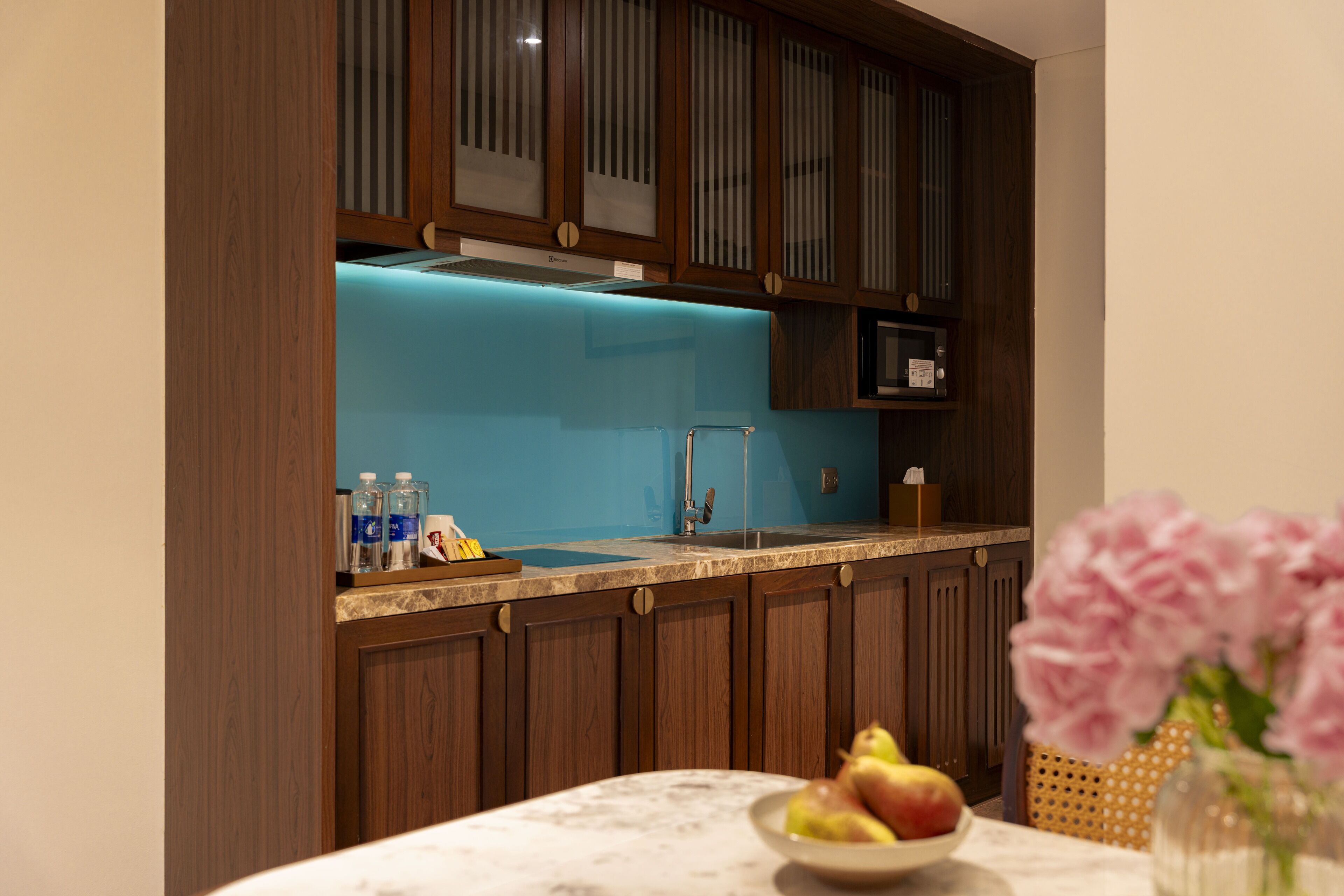 A kitchen with wooden cabinets, a blue backsplash, and a marble countertop.