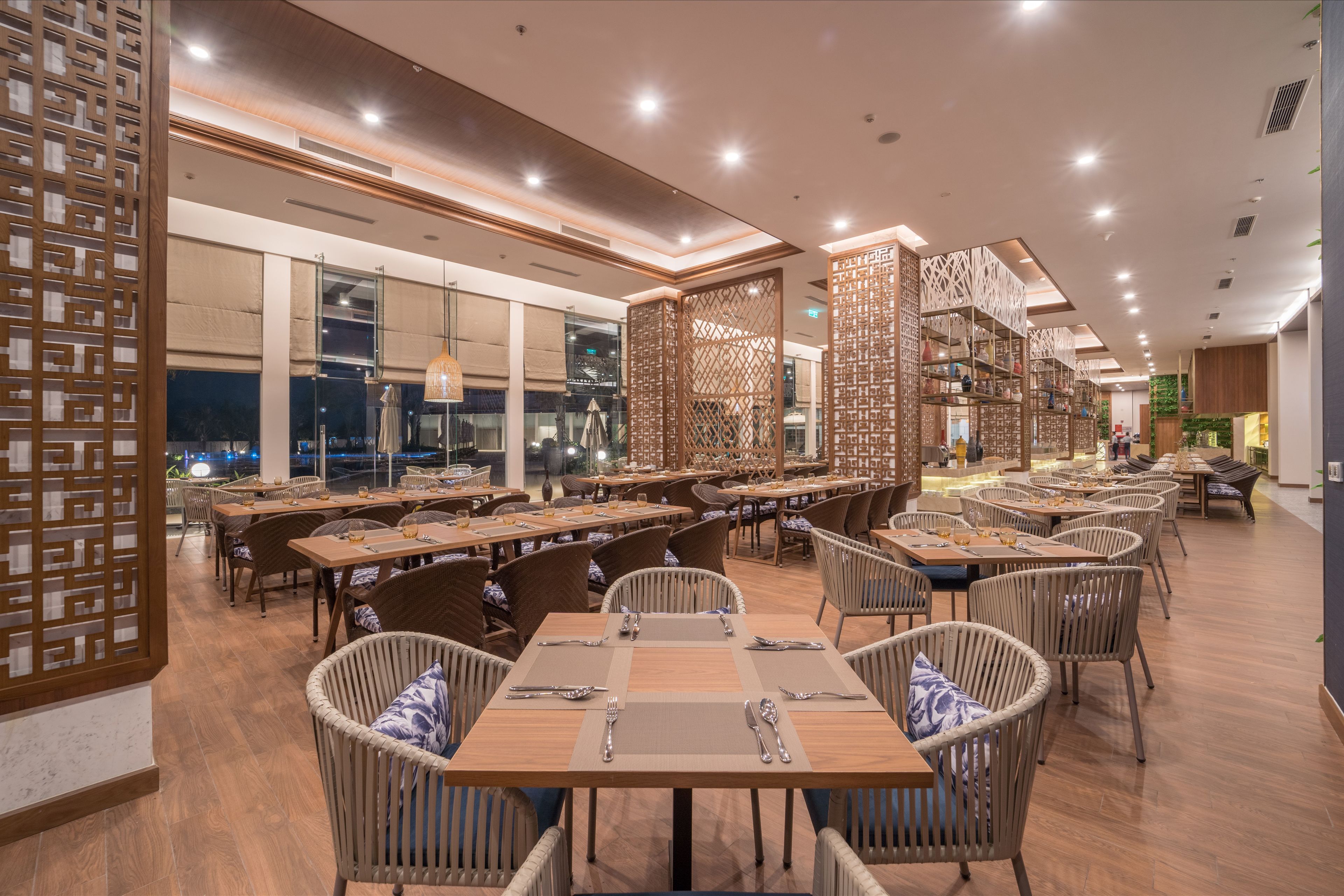 Un restaurante espacioso con varias mesas y sillas, pisos de madera y una decoración de estilo moderno.