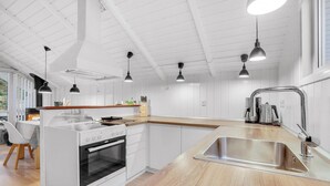 Une cuisine moderne avec des meubles blancs, un plan de travail en bois et un évier en acier inoxydable.