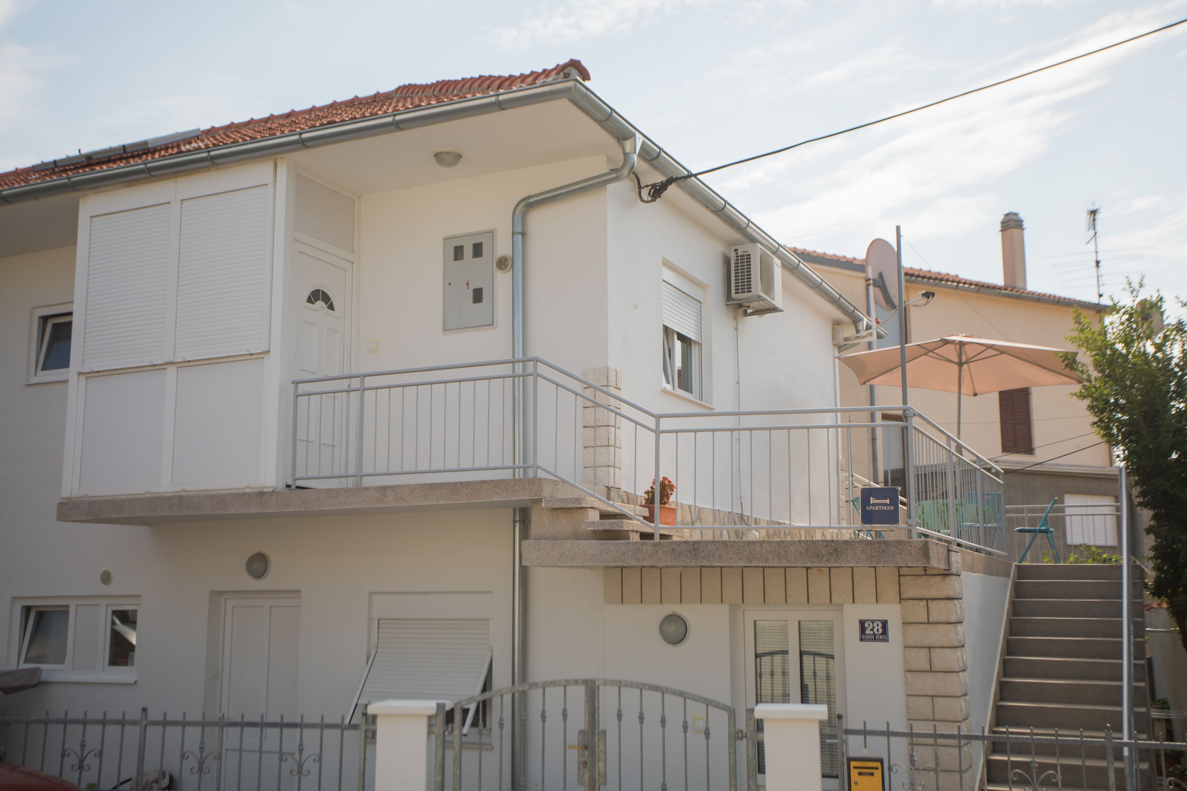 A two-story building with a balcony, a staircase, and a door marked with the number 28.