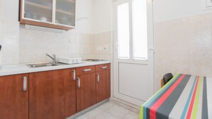 A kitchen with wooden cabinets, a sink, and a window. - Apartments Ana (Vodice)