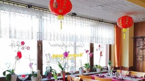 A dining area with tables set for multiple guests, featuring red tablecloths and wooden chairs. - Hotel Quellenhof (Bad Breisig)