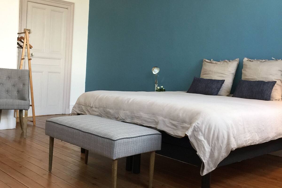 Una camera da letto con un letto, una panca e un lampadario.