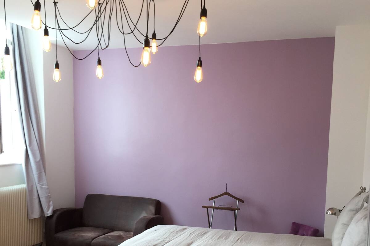 Una camera da letto con un letto, una sedia, un lampadario e un tavolino con una pianta.