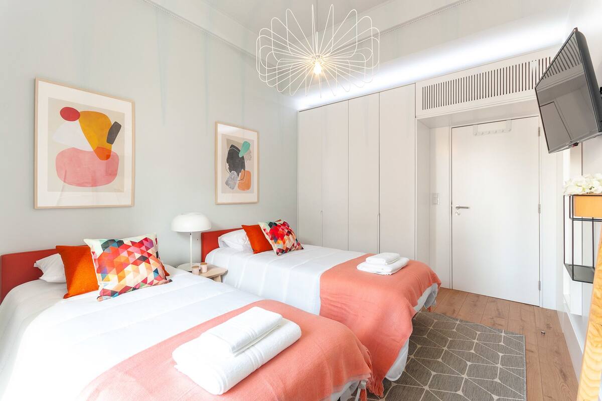 Ein Hotelzimmer mit zwei Betten, einem Fernseher, einem Kleiderschrank und Bildern an den Wänden.