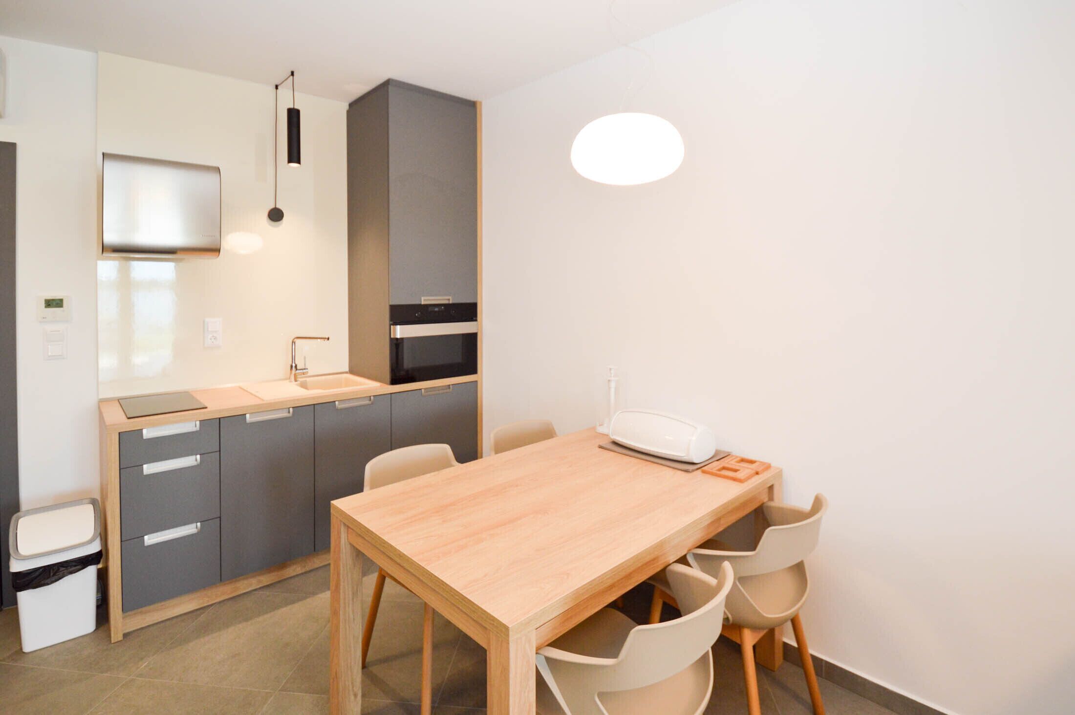 A compact kitchen with a wooden table and chairs, a microwave, and a sink.