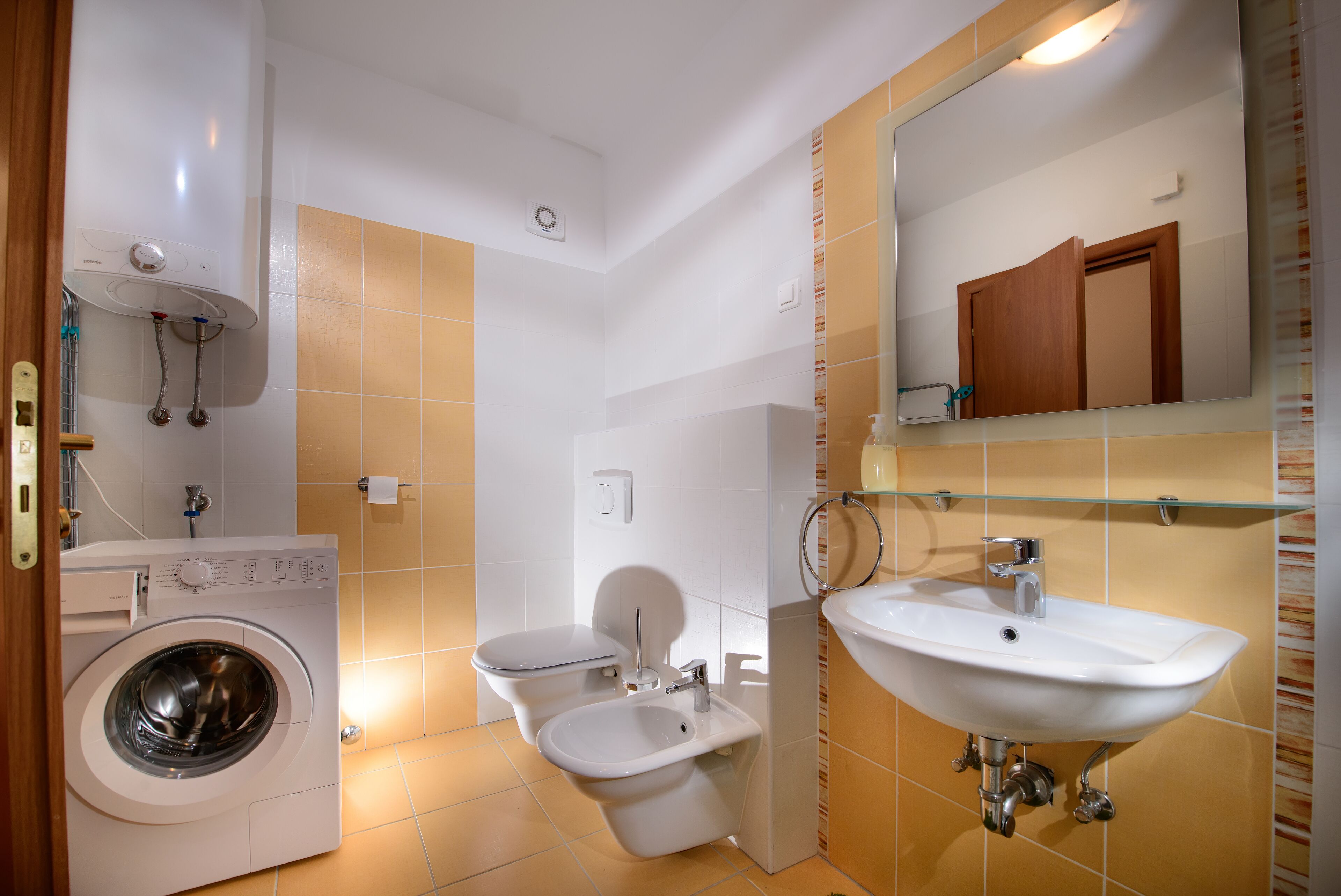 Ein kleines Badezimmer mit Waschmaschine, Toilette, Bidet und Waschbecken.
