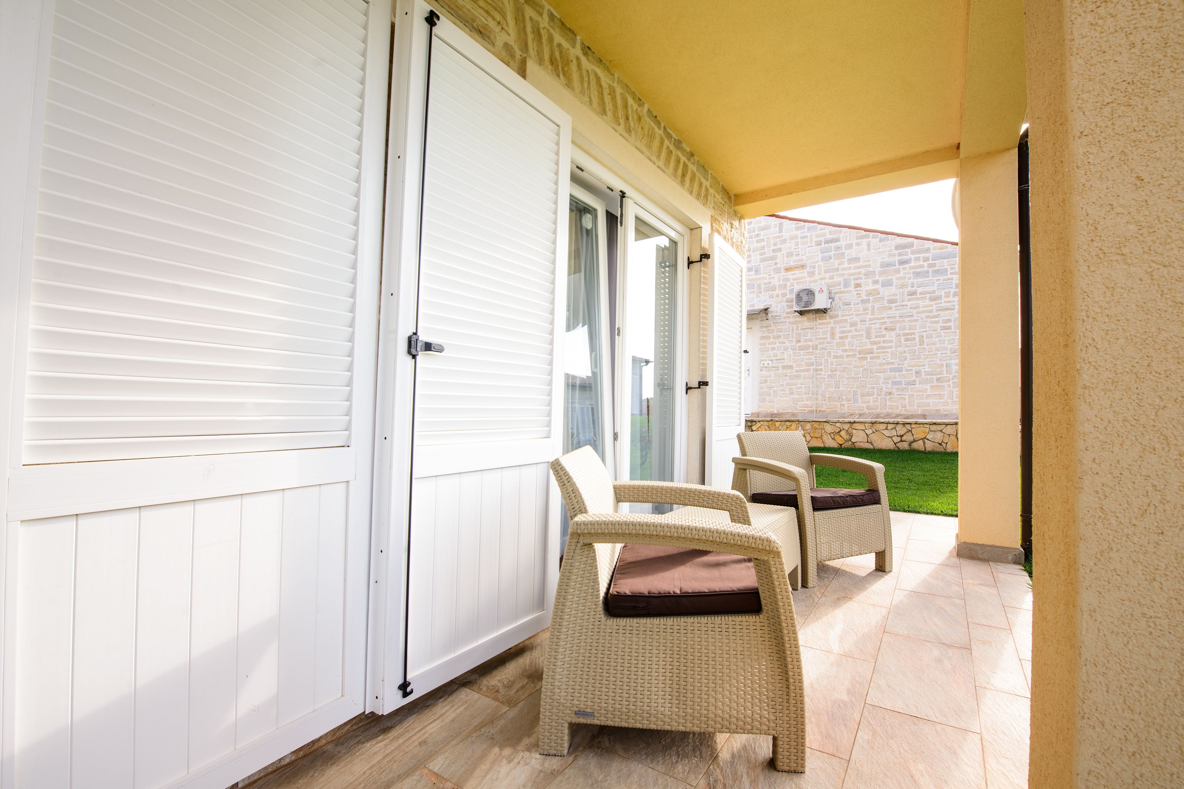 Ein überdachter Patio-Bereich mit Korbmöbeln und einer weißen Tür.