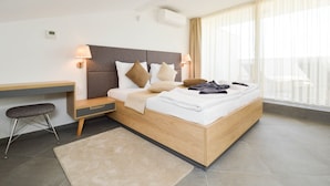 A modern hotel room with a wooden bed, bedside lamps, a desk, and a view of the outdoors. - Plavo Nebo Istra Apartments (Medulin)