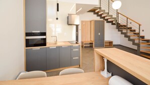 A modern kitchen with grey cabinets, a wooden countertop, and a built-in oven. There is a staircase with a wooden railing leading to a landing. - Plavo Nebo Istra Apartments (Medulin)