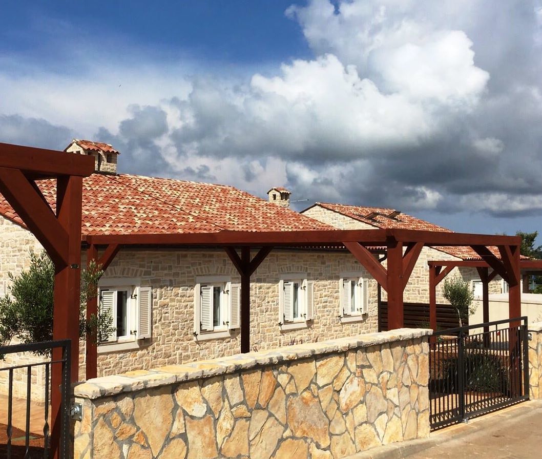 Un bâtiment en pierre avec un toit en tuiles, un mur en pierre et un portail en métal.