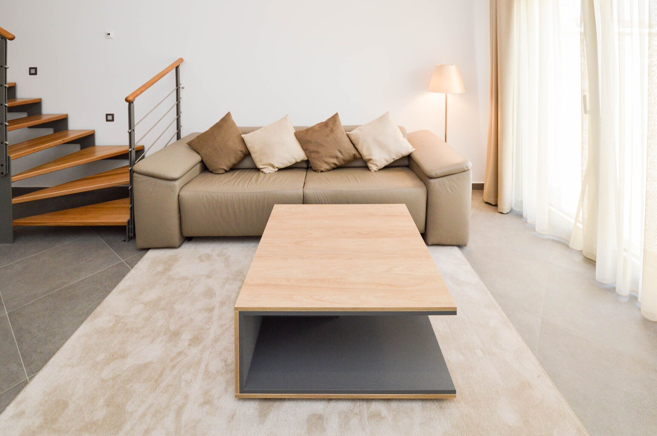 Uma sala de estar moderna com um sofá, uma mesa de centro, uma escada e um abajur.