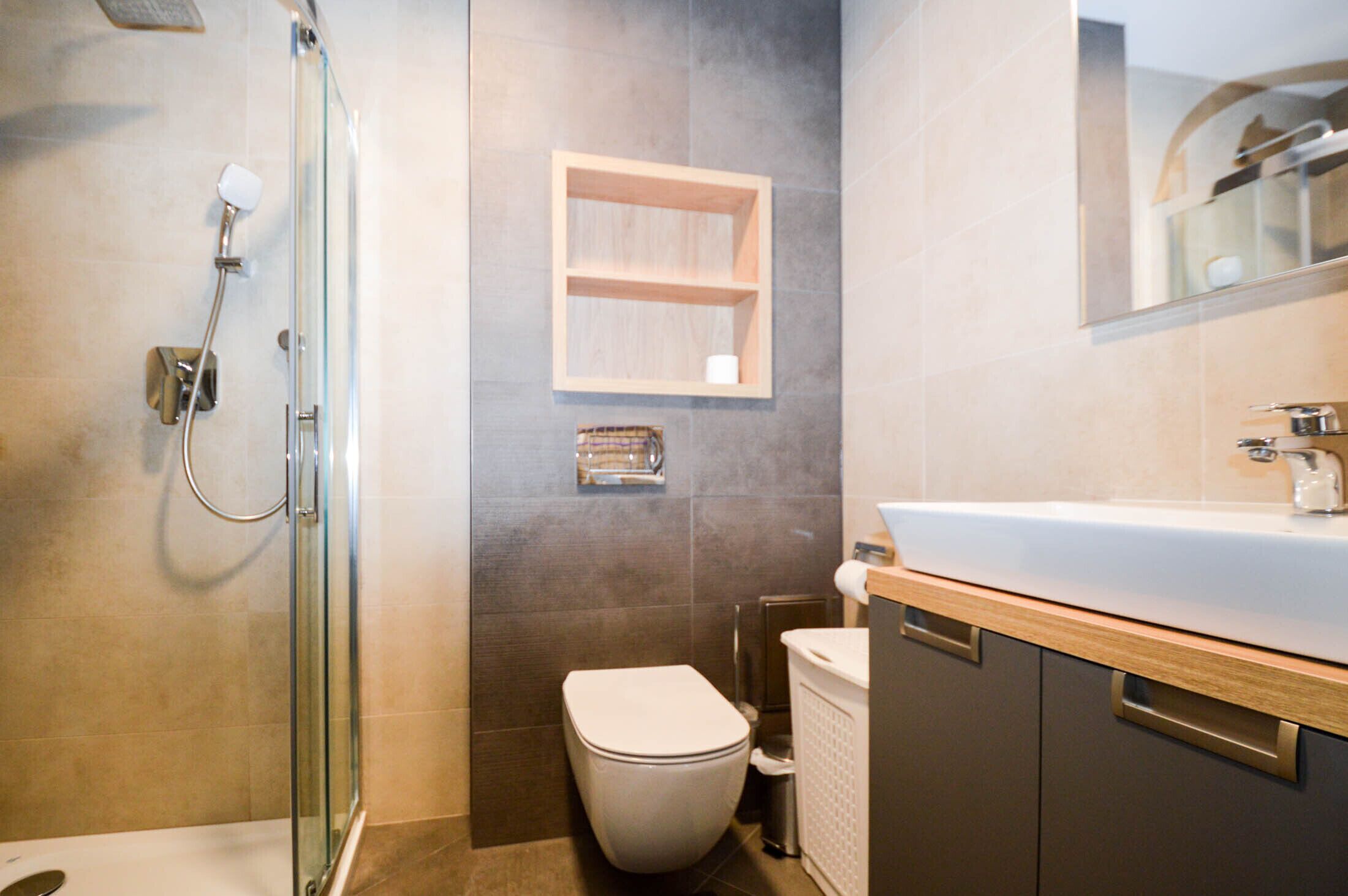 Une salle de bain moderne avec une douche à parois de verre, des toilettes et un meuble-lavabo avec un miroir.
