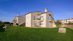 A two-story stone house with a balcony, a staircase, and a well-maintained lawn. - Plavo Nebo Istra Apartments (Medulin)
