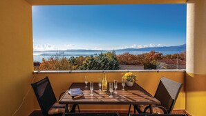 A balcony with a table set for two, overlooking a scenic view of a lake and mountains. - Stunning apartment in Kostrena with WiFi (Kostrena)