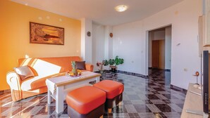 A modern living room with a sofa, ottomans, a table with fruit, a potted plant, and a painting on the wall. - Stunning apartment in Kostrena with WiFi (Kostrena)