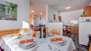 A dining area with a round table set for four, surrounded by chairs, with a kitchen visible in the background. - Stunning apartment in Kostrena with WiFi (Kostrena)