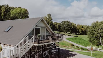 En tvåvåningsbyggnad med en balkong, en grund av sten och utsikt över en golfbana.