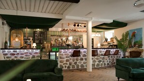 A bar area with a stone wall backdrop, green upholstered seating, and a variety of bar stools. - Skyrup Golf & Hotell (Tyringe)