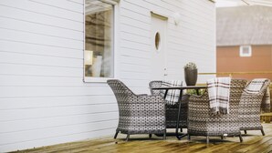 A white building with a window and a door, a table with chairs, and a potted plant. - Skyrup Golf & Hotell (Tyringe)
