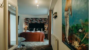 Un dormitorio con una cama, una mesita de noche, un espejo y un cuadro en la pared.