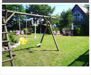A wooden swing set in a grassy yard with a house in the background.