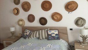 A bedroom with a bed, pillows, and a wall adorned with various hats. - A Pochi Passi dal Mare di Marciana Marina (Marciana Marina)
