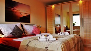 Quarto de hotel com uma cama, um espelho grande e uma pintura do pôr do sol.