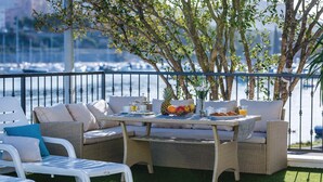 A balcony with wicker furniture, a table with fruits and drinks, and a view of the water. - Amazing home in Sibenik (Sibenik)
