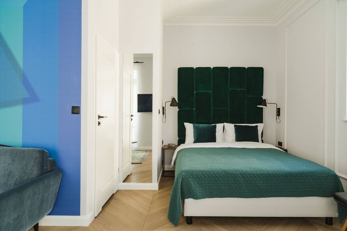 Un dormitorio con cama, mesita de noche, lámpara y una silla.