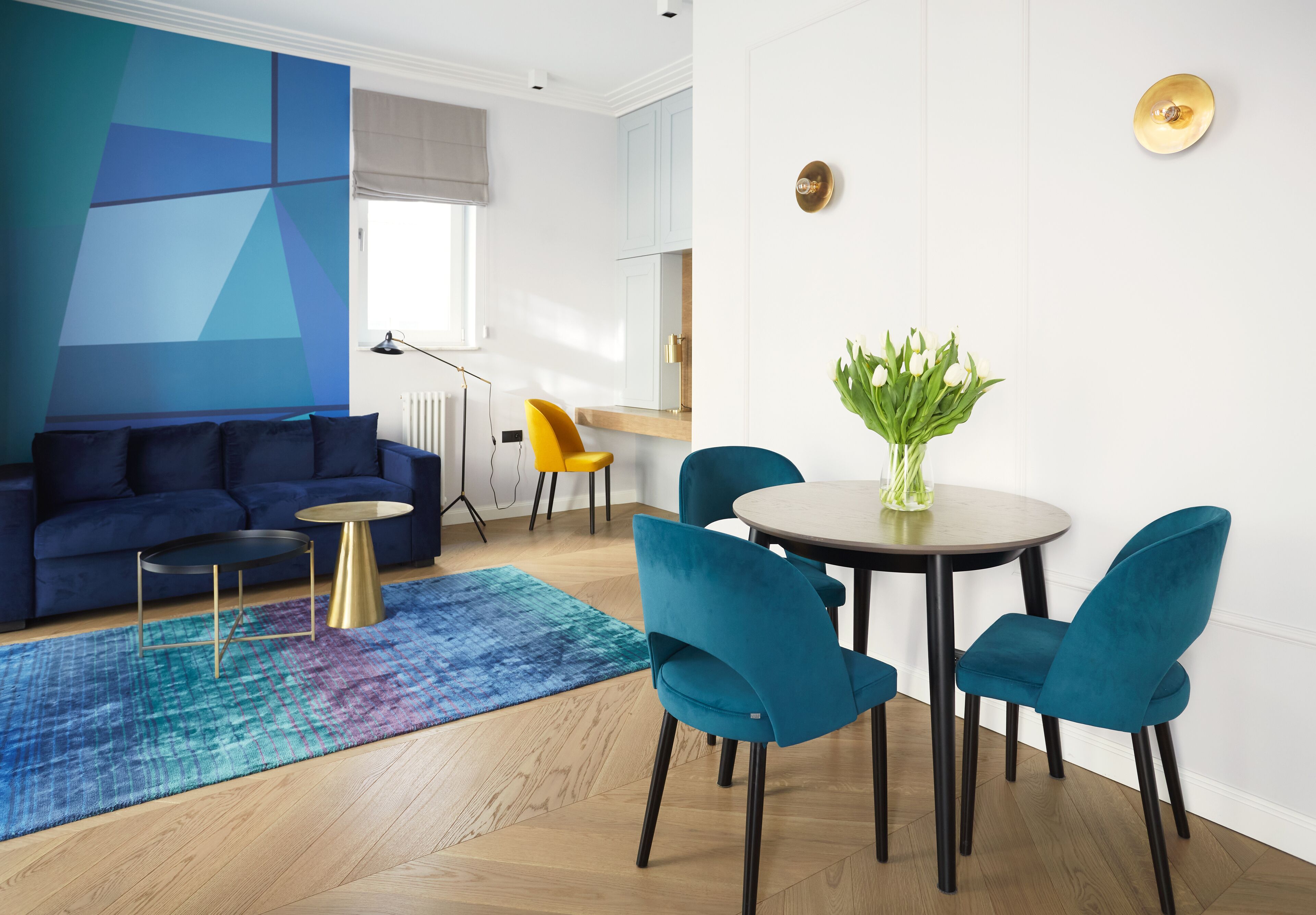 Un salon moderne avec un canapé bleu, une table ronde et des chaises de couleur turquoise.