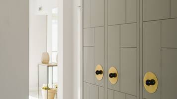 A hallway with a grey tiled wall, a white floor, and a door with a circular handle.