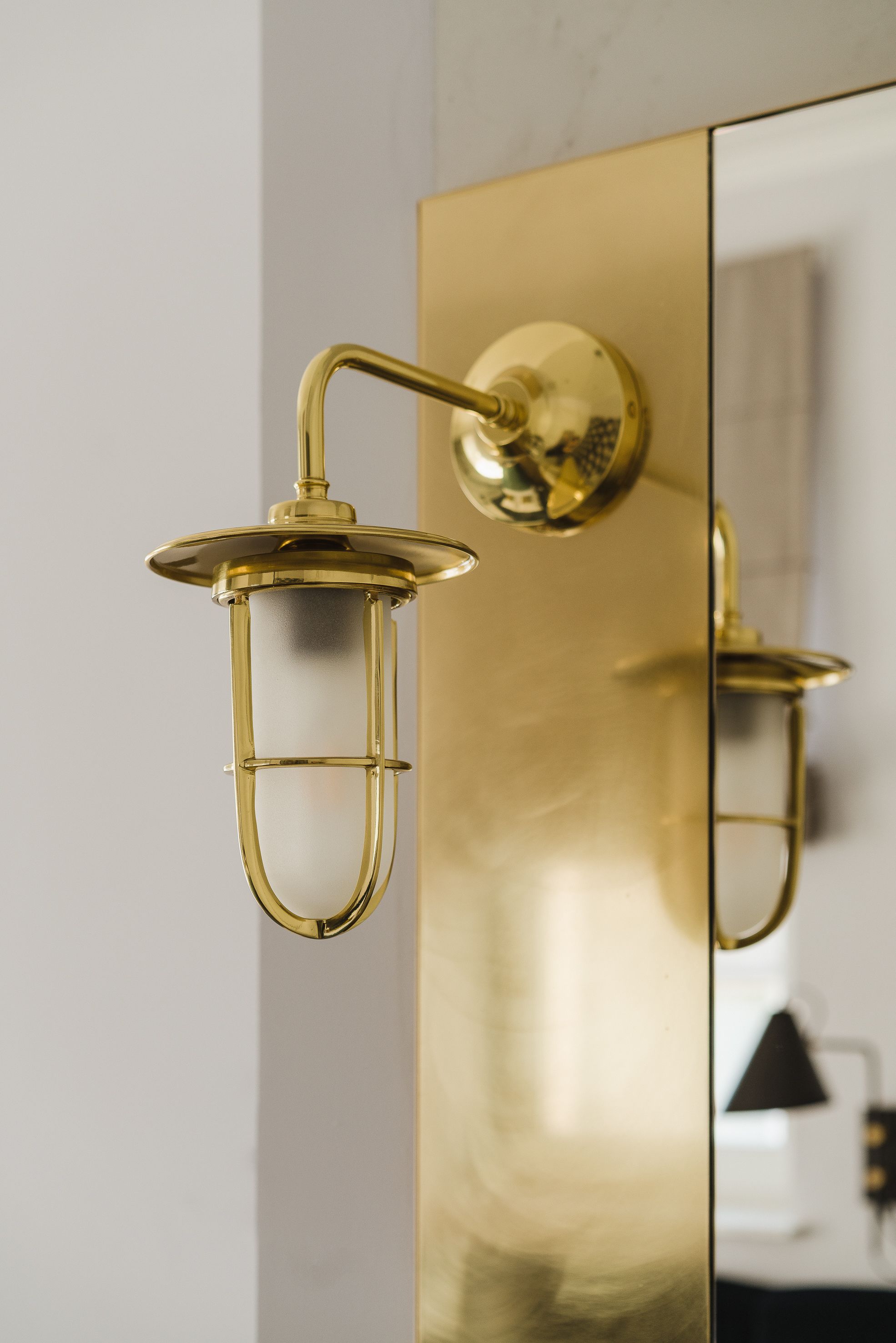 Eine goldfarbene, wandmontierte Leuchte mit zylindrischer Form und einer reflektierenden Oberfläche.