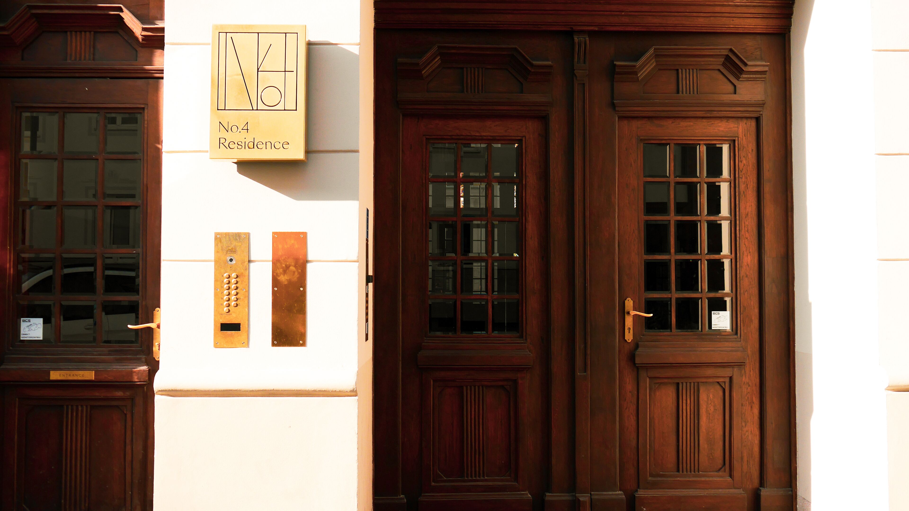 Una puerta de madera con un panel de vidrio, un timbre de latón y un letrero que indica 'No.4 Residence'.