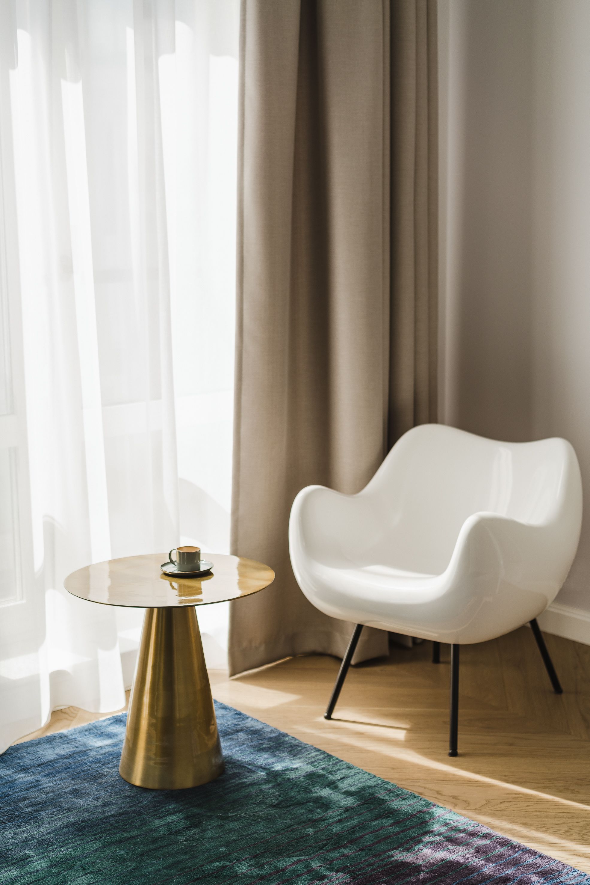 A modern room with a round glass table, a white chair, and a patterned rug.