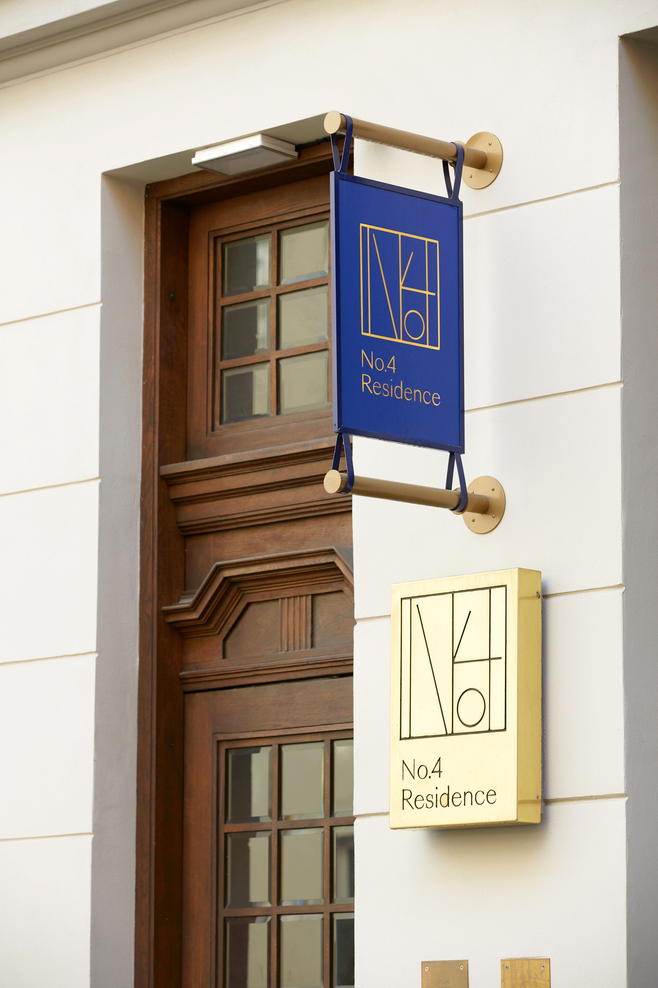 A building with a blue sign indicating 'No.4 Residence' and a gold sign with the same text.