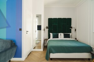 A bedroom with a bed, a nightstand, a lamp, and a chair.