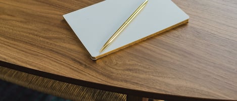 A wooden table with a notebook and pen, a gold tray, and a patterned rug.