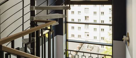 A spiral staircase with metal railings and a view of a residential building through a large window.