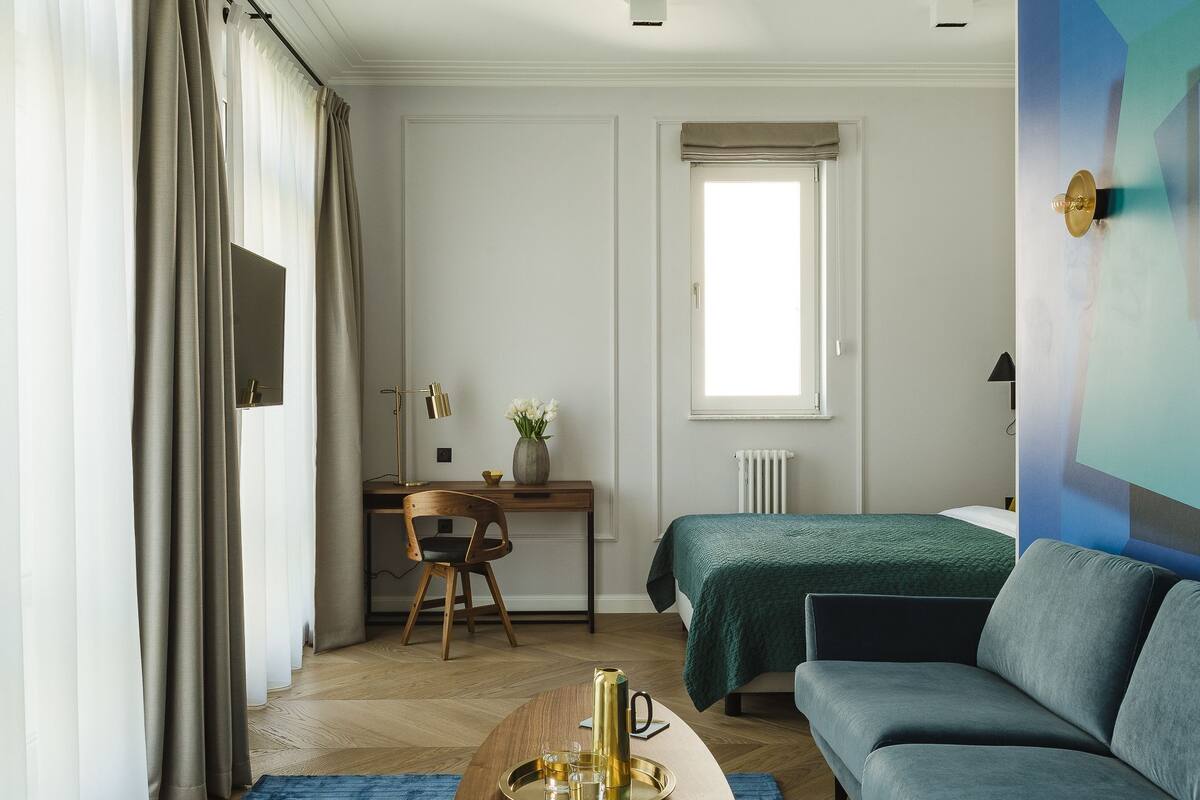 Una habitación de hotel moderna con una mesa de centro de madera, un sofá, un escritorio y una cama.