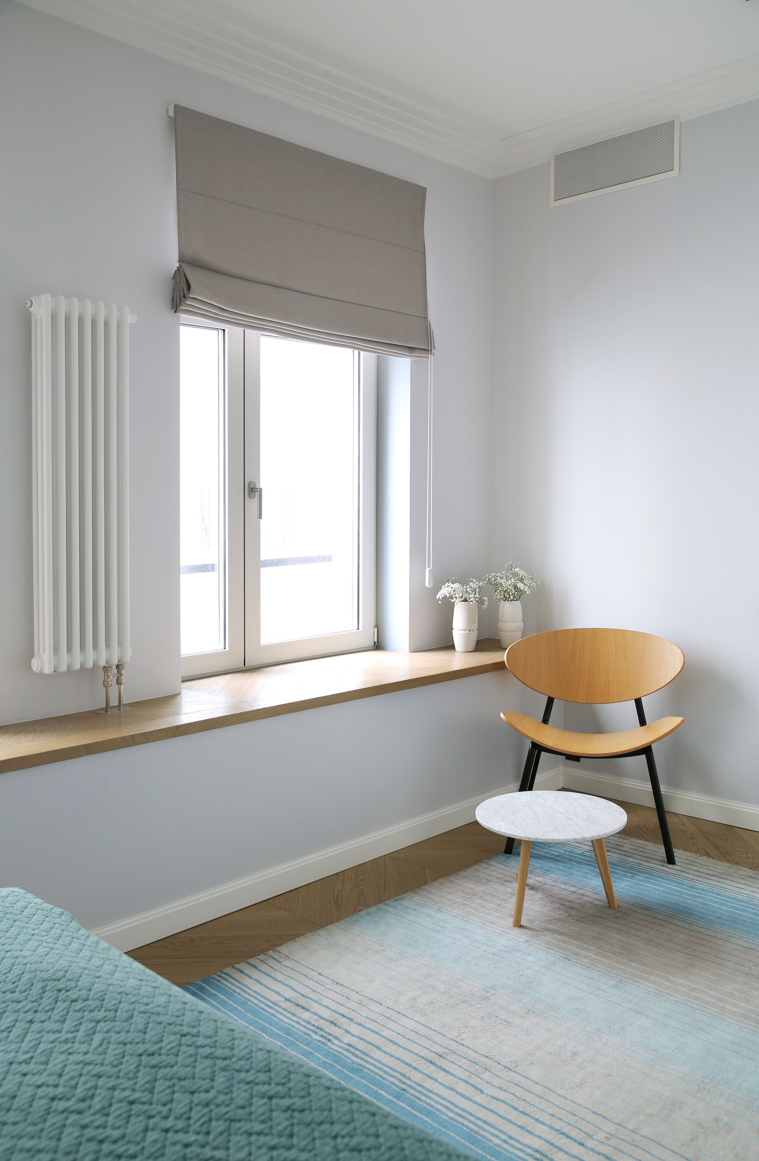 A room with a window, radiator, wooden floor, and a chair.