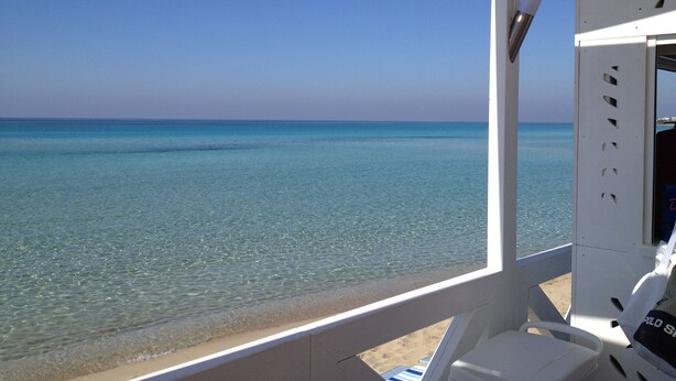Une vue sur la plage depuis un espace abrité, avec un ciel dégagé.